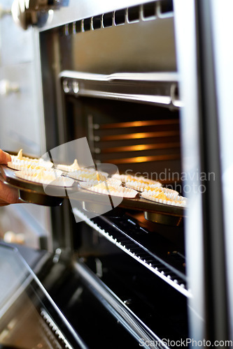 Image of Hands, closeup and tray in oven for cupcake, baking and food for small business, cafe or restaurant. Professional chef, baker or person with muffin in bakery, coffee shop or food industry startup
