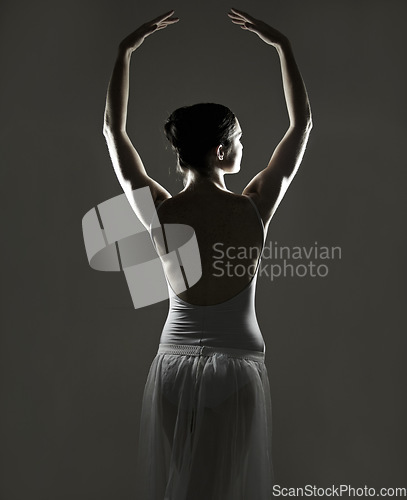 Image of Art, silhouette and back of a ballet dancer in a studio with elegant posture, pose or position. Creative, monochrome and female ballerina doing a classical dance or performance by a black background.