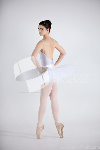 Image of Portrait, dance and ballet with a woman in studio on a white background for theatre performance rehearsal or recital. Art, creative and back with a young ballerina or dancer standing hands on hips