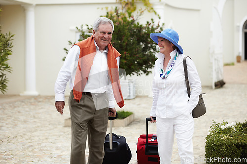 Image of Travel, vacation and senior couple walking with suitcase in a holiday location happy in retirement together by a hotel. Bag, smile and elderly people on a journey or man and woman walk in happiness