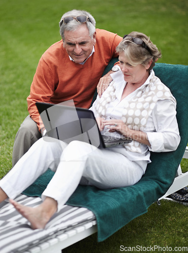 Image of Retirement, laptop and an old couple in the garden of a hotel for travel or vacation at a luxury resort. Love, technology or social media with a senior man and woman tourist on a deckchair at a lodge