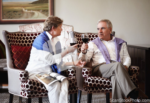 Image of Toast, love and an old couple drinking wine in their hotel room while on holiday or vacation together. Retirement, sofa or relax with a senior man and woman bonding at a luxury resort for romance