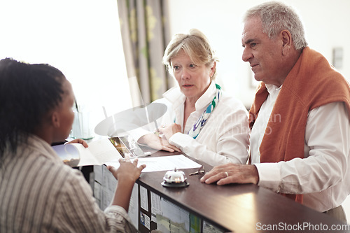 Image of Reception, hotel and senior couple on vacation or elderly person at concierge, desk or check in with lobby receptionist or secretary. Black woman, working in hospitality and help people in retirement