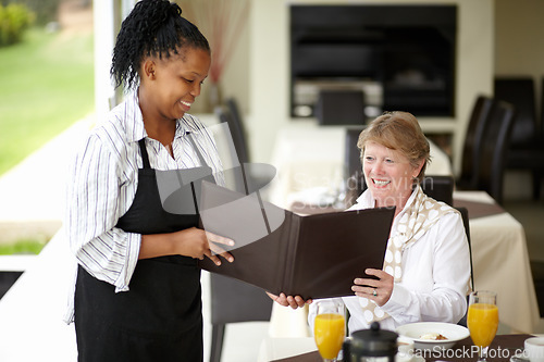 Image of Waitress, service and senior woman in a restaurant for breakfast or lunch at a hotel with a menu and choice of food. Friendly, order and elderly person happy on vacation or holiday for hospitality