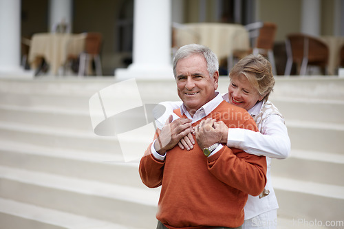 Image of Hug, hospitality and an old couple on hotel steps for travel, vacation or tourism in luxury accommodation. Love, relax or retirement with a senior man and woman hugging on the staircase of a resort