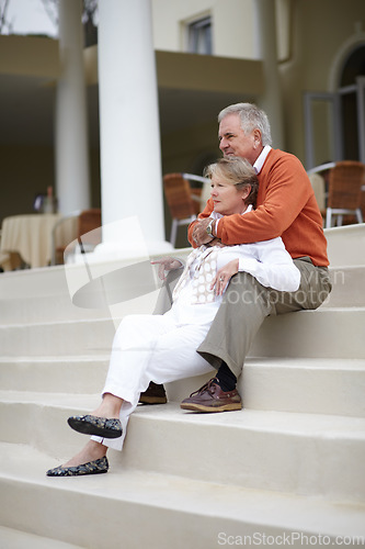 Image of Hug, love and an old couple on hotel steps for travel, vacation or tourism in luxury accommodation. Retirement, relax or hospitality with a senior man and woman hugging on the staircase of a resort