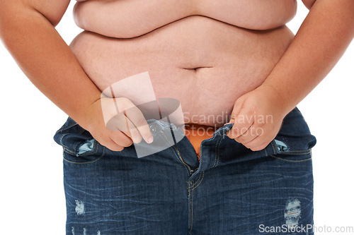 Image of Weight gain, plus size and jeans of a person with overweight and stomach issue in studio. White background, model and casual fashion too tight from stomach and waist wellness problem of pants