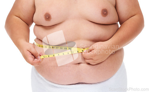 Image of Overweight, tape measure and man checking wellness progress and weight loss goal in studio. White background, hands and model with plus size stomach with body problem and health issue with towel