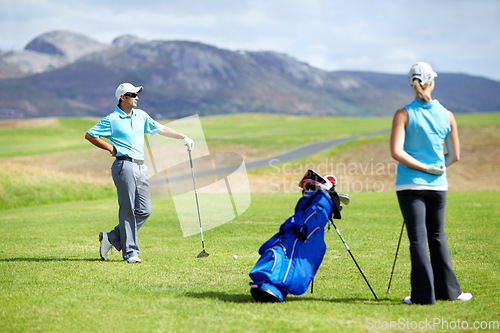 Image of Couple, teamwork or golfer playing golf for fitness, workout or exercise together on green course field. Healthy people, woman golfing or athlete training in action or sports game driving with clubs