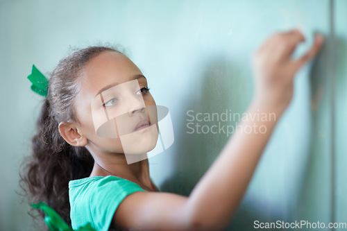 Image of Education, focus and a girl writing on a chalkboard for learning, studying and teaching in class. Creative, concentration and a young student at a blackboard for a presentation or classroom notes