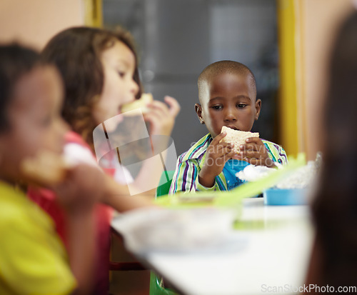 Image of Eating, boy and children class for lunch at school or creche for an education or to learn. Break, kid and sandwich in a classroom to eat or learning or hungry at desk for nutrition with friends.