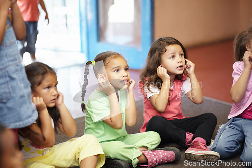 Image of School children on floor listening to teacher for anatomy education, hearing exercise and learning in classroom. Class, group and kids on ground with attention, discipline and kindergarten or creche