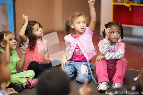 Image of Education, kindergarten and kids asking a question with hands raised while sitting on a classroom floor for child development. School, learning or curiosity with children in class to study for growth