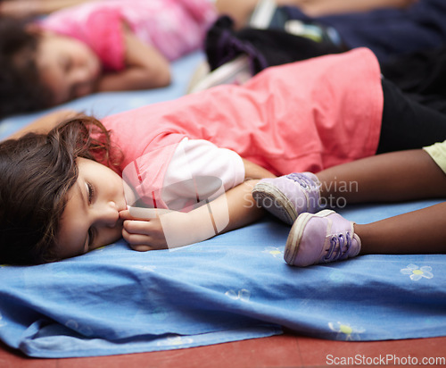 Image of Kindergarten, children and group sleeping, relax and resting after education. Nursery, sleep and tired students take nap to rest together after learning, studying and knowledge in preschool classroom