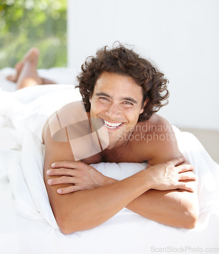 Image of Portrait, happy and weekend with a man on a bed in his home to relax or rest on a summer morning. Smile, wellness and bedroom with an attractive young male person relaxing alone in his house