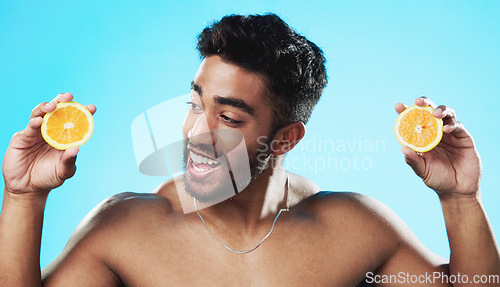 Image of Skincare, orange and face of man in studio for beauty, wellness and citrus treatment on blue background. Fruit, facial and portrait of indian male model excited for organic vitamin c skin cosmetics