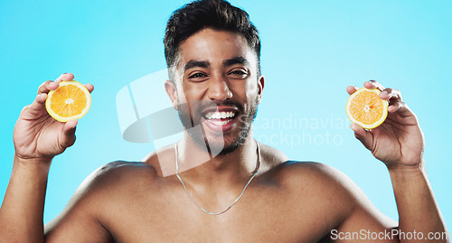 Image of Skincare, orange and face of man in studio for beauty, wellness and citrus treatment on blue background. Fruit, facial and portrait of indian male model excited for organic vitamin c skin cosmetics