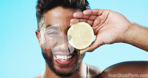 Image of Skincare, lemon and face of man in studio for beauty, wellness and citrus treatment on blue background. Fruit, facial and portrait of indian guy model relax with organic, anti aging or skin cosmetics