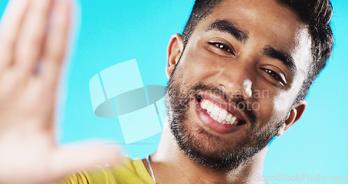 Image of Selfie, laughing and face of a man with a smile isolated on a blue background in a studio. Happy, cheerful and portrait of a young guy taking a photo, smiling and posing for a picture on a backdrop