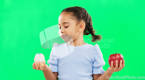 Image of Face, confused and child on green screen with apple, candy and deciding in studio on mockup background. Portrait, fruit or dessert for girl unsure, doubt and contemplating snack while posing isolated