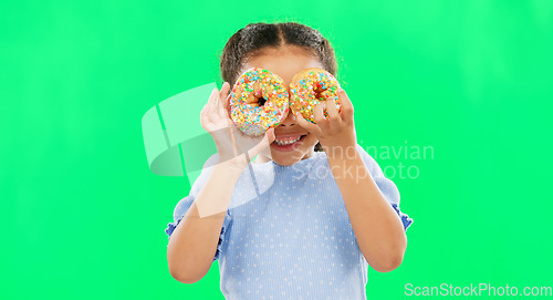 Image of Donut on eyes, smile and child on green background with cake over face for funny, meme and comic. Food, excited kid and isolated happy girl with sweets, dessert treats and sugar doughnuts in studio