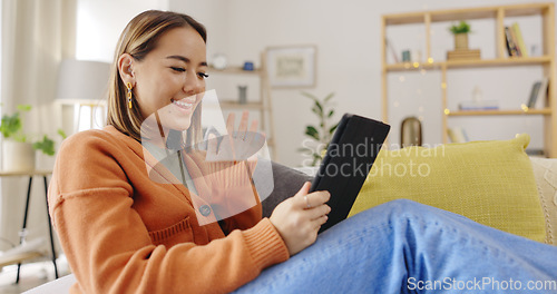 Image of Video call, sofa and woman on tablet waves hello for virtual communication, talking and social networking. Home, happy and asian person relax on couch with digital technology and online web chat