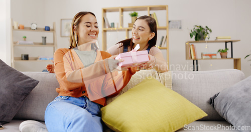 Image of Home, lesbians and couple with a surprise, gift and bonding in living room, happiness and relax. Partners, women and queer people in their lounge, present and celebrate relationship, marriage and wow