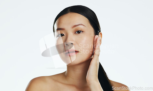 Image of Skincare, asian woman and touch face in studio for beauty, dermatology or cosmetics on white background. Female model, portrait and facial aesthetic glow of shine, laser transformation and wellness