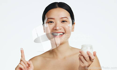 Image of Face, lotion and beauty of asian woman, studio and isolated white background of aesthetic cosmetics. Portrait, facial cream and skincare jar of female model, sunscreen and happy dermatology product