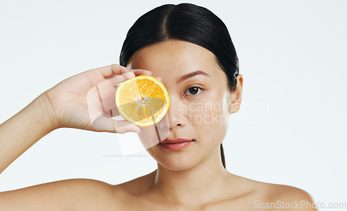 Image of Orange fruits, skincare and face of woman in studio, white background and cosmetics. Beauty model, asian female and portrait of citrus for vitamin c, natural detox and healthy aesthetic dermatology