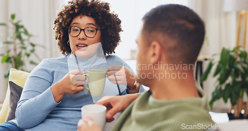 Image of Interracial happy couple, conversation and coffee on sofa for morning bonding in living room together. Discussion, woman and man on couch with tea, quality time to relax, talk and plan day in lounge.