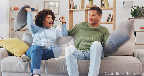 Image of Pillow fight, happy couple and fun in living room for love, silly game and energy at home. Cushion, fighting and excited man being playful with young woman, partner and laughing together on couch