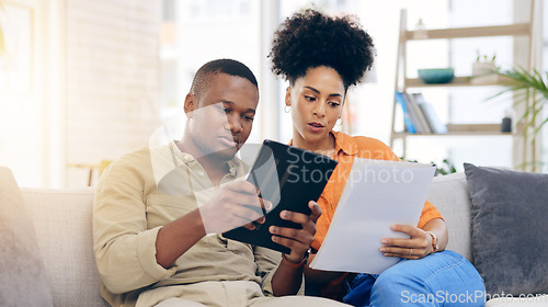 Image of Black couple,tablet, documents and financial crisis on living room sofa discussing mortgage payment or loan at home. Frustrated African man and woman with paperwork in debt, finance issue or money pr