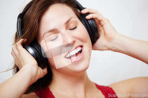 Image of Music, headphones and singing by happy woman in studio with audio, track or song on white background. Earphones, face and female person streaming podcast, radio or online playlist and subscription