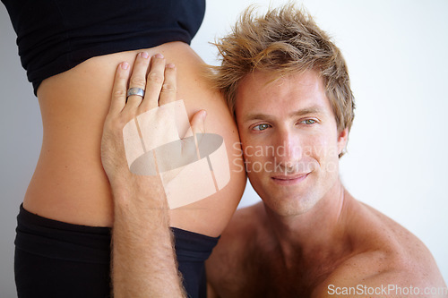 Image of Man listening with head on stomach, pregnant woman and excited new parents in studio on white background. Love, support and pregnancy, mother and father with hand on belly and future baby in family.