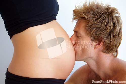 Image of Man kissing stomach, pregnant woman and love, excited new parents in studio on white background. Marriage, support and pregnancy, mother and father with baby in belly and couple with future family.