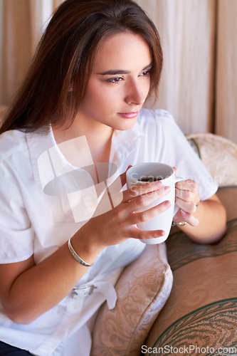 Image of Relax, woman drinking her coffee in the morning and thinking on sofa in the living room of her home. Peace or freedom, health wellness and female person drink hot beverage for stress relief