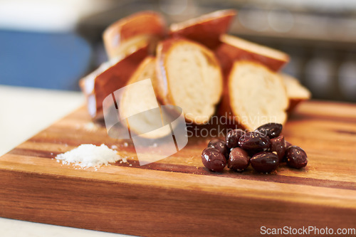 Image of Olives, food and bakery with bread in kitchen for nutrition, health and diet. Breakfast, cafe and coffee shop with closeup of product on cutting board on table for wheat, grain and cooking