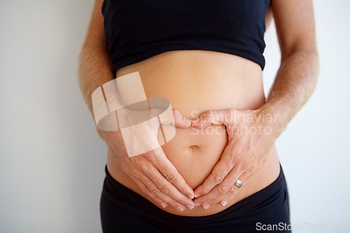 Image of Closeup, pregnant and woman with heart hands, stomach and health with childbirth, support or wellness. Zoom, pregnancy or female person touching belly, tummy or symbol for love with maternity or care