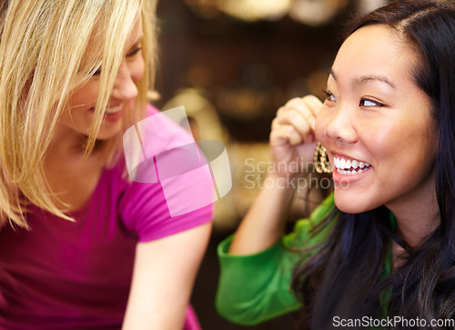 Image of Jewelry, retail and friends shopping in a mall together for earrings or accessories with a smile. Diversity, sales or fashion with an asian woman customer and her best friend bonding in a store