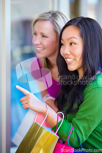 Image of Window shopping, women and bags at a mall for sale, discount and boutique promotion, happy and excited. Hand pointing, store and friends smile while talking and checking items together on the weekend