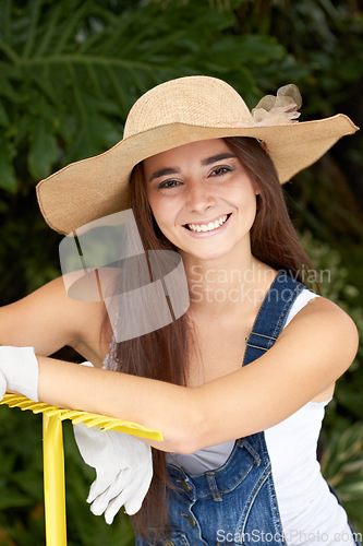 Image of Young woman with rake, smile and gardening in portrait with nature, Spring time and blossom. Sustainability, planting and agriculture while happy female gardener is backyard and outdoor landscaping