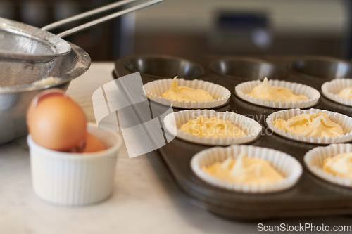 Image of Cupcake tray, batter and baking in a kitchen with muffin mix or wrapper and cooking in a bakery. Closeup, paper cup and food with chef in a restaurant, coffee shop or cafe with sweet cake and pastry