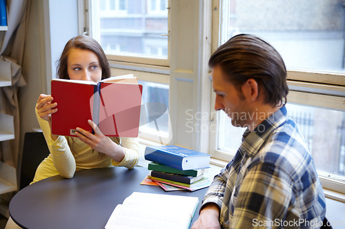 Image of Education, college and couple studying in a library, learning and reading books together. Scholarship, focus and a man and woman sitting at a university table for research, knowledge and information