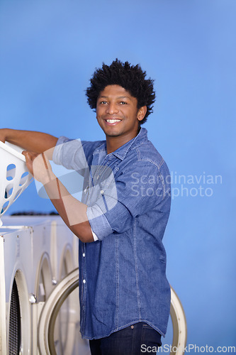 Image of Laundry, portrait of a black man at washing machine and basket at laundromat with a smile. Hygiene, service and African male person cleaning clothes for health wellness or protection from bacteria