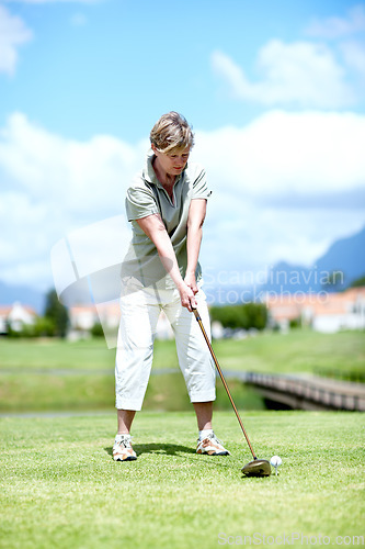 Image of Senior, woman or golfer playing golf for fitness, workout or stroke exercise on a course in retirement. Mature, golfing or serious lady player training in sports game driving with her club or driver