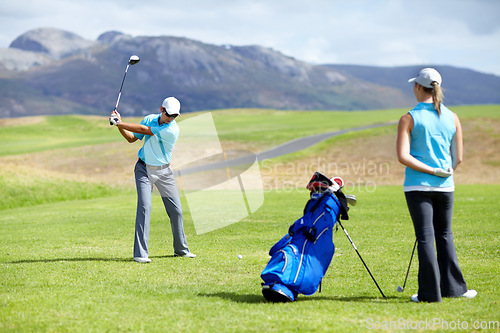 Image of Swing, man or golfer playing golf for fitness, workout or exercise to drive on a green course. Woman, person golfing or athlete training in action or sports game driving with a club stroke on field