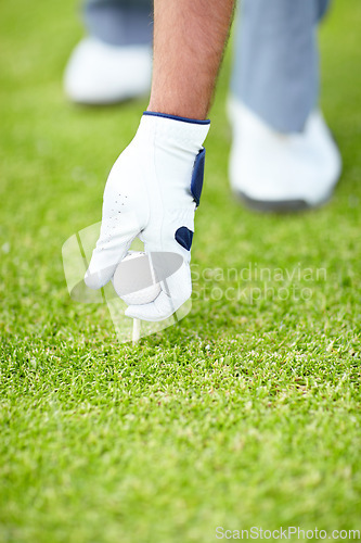 Image of Golf ball, sports or hand of man on the grass course outside ready to start golfing with gloves for training. Fitness, holding or closeup of athlete golfer with tees or pin on field in game practice