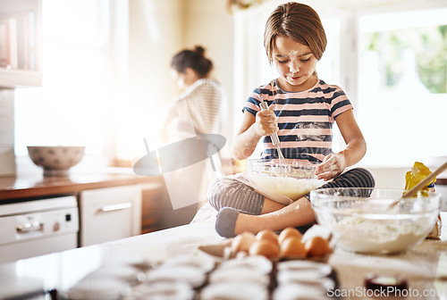 Image of Messy, flour and girl baking in a kitchen with parent for learning about Independence, child development or food at home. Dirty, fun or young female kid mixing cake or cookies in a bowl while cooking
