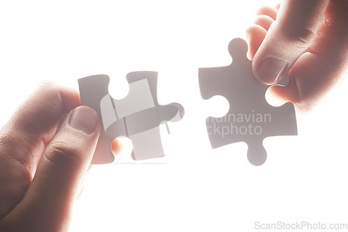 Image of Puzzle, synergy and solution with hands of person on white background for achievement, goal and development. Mission, game and cooperation with jigsaw pieces for support, success and integration